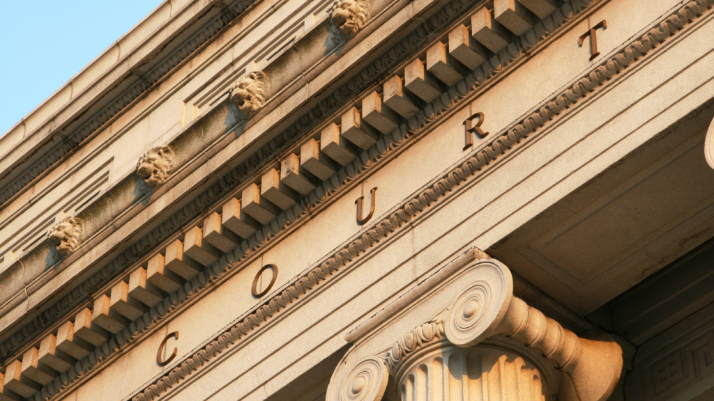Close-up view of a courthouse facade with stone lions and the word "COURT" engraved, symbolizing the legal system and the impact of Georgia tort reform on law firms.
