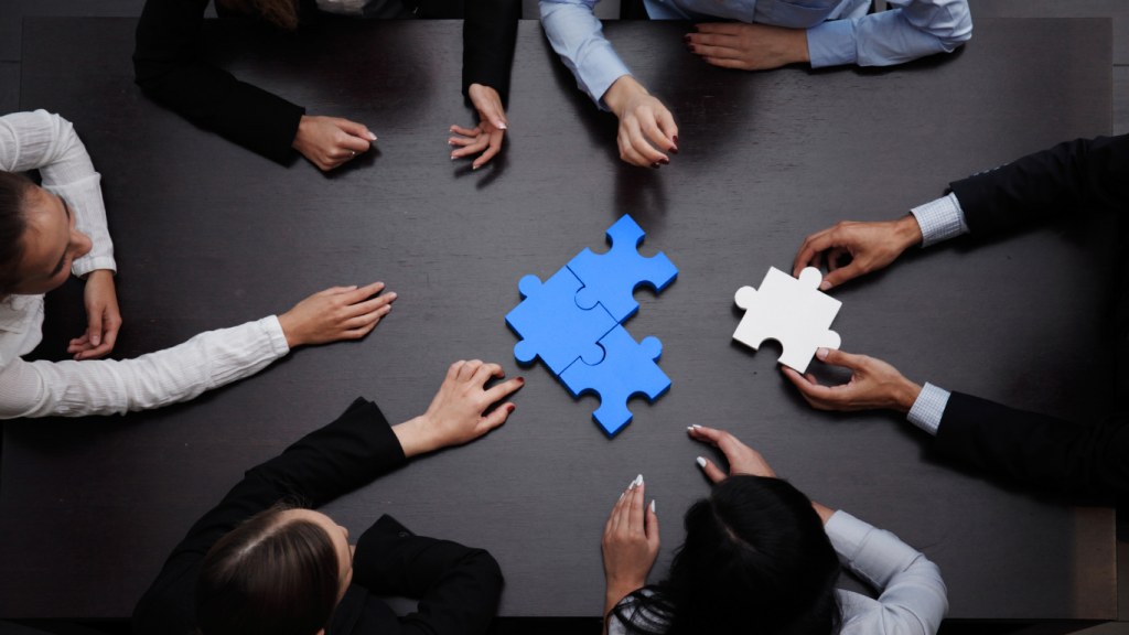 Attorneys and team members connecting puzzle pieces on a table to represent collaboration and case management in personal injury law.